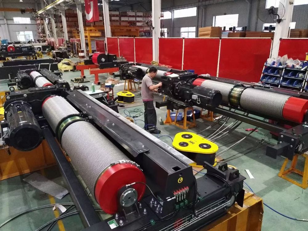 Row of wire-rope electric hoists under inspection