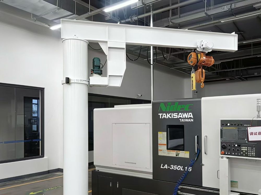 Wall-mounted jib crane serving a CNC lathe