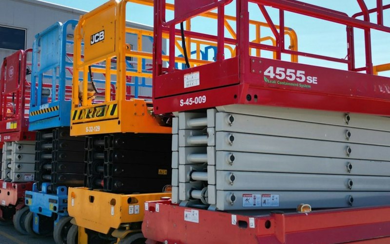 Red scissor lift platform raised on a work site